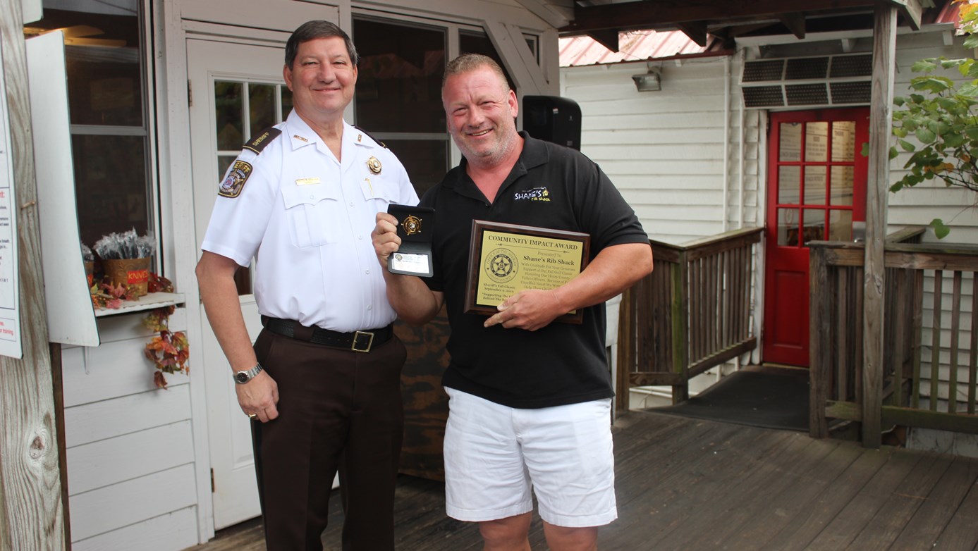 Sheriff Keith McBrayer and Shane Thompson holding the Honorary Deputy Badge and Community Impact Award